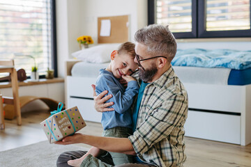 Dad get a handmade gift from little son, present wrapped in diy homemade wrapping paper. Happy...