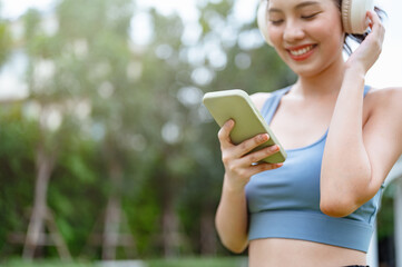 sporty, fitness, exercise, run, runner, sports, jogging, training, jogger, health. A woman is smiling while holding a cell phone. She is wearing headphones and she is listening to music.