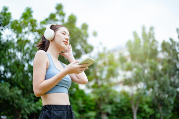 run, fit, runner, jogging, jogger, health, relaxation, sport, fitness, training. A woman in a park while listening to music and holding a smartphone. and wearing headphones, enjoying her time outdoors