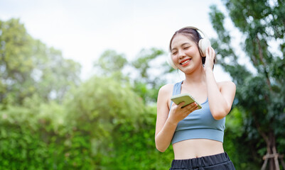 run, runner, fit, sports, women, jogging, smiling, jogger, health, training. A woman is walking in a park while listening to music. She is wearing a blue top and black pants.
