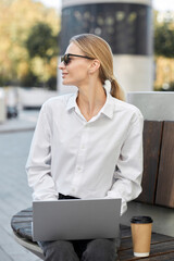 Young pretty blond woman with ponytail hairstyle dressed in a white blouse, black jeans and...