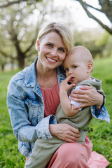 Portrait of beautiful mature first time mother with small toddler, outdoors in spring nature.