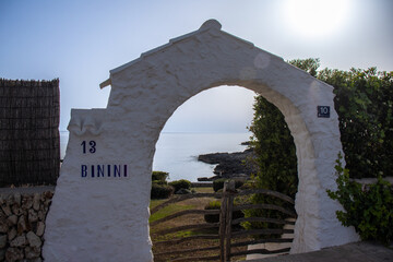 White arch through which you can see the sea, near the town of Binibeca Vell. Menorca, Spain