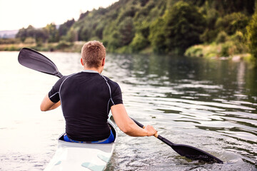 Canoeist man sitting in canoe holding paddle, in water. Concept of canoeing as dynamic and...