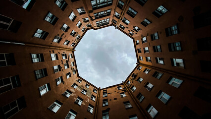 Looking up at circular courtyard of an old apartment building with an octagonal sky view. Urban architecture - obrazy, fototapety, plakaty