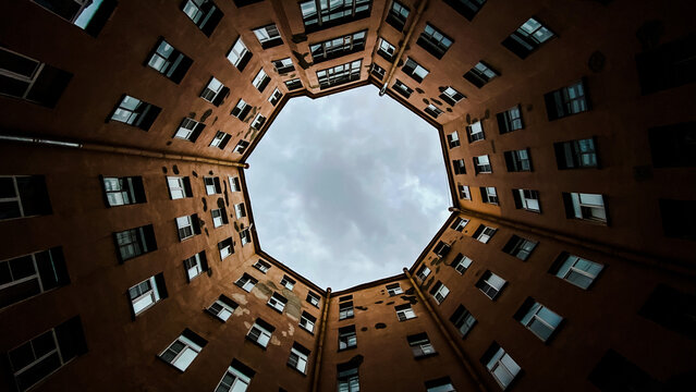Looking up at circular courtyard of an old apartment building with an octagonal sky view. Urban architecture