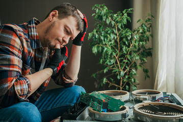 Focused technician sits in suspense, studying and troubleshooting the cooking surface. Repair of an electric stove at home.