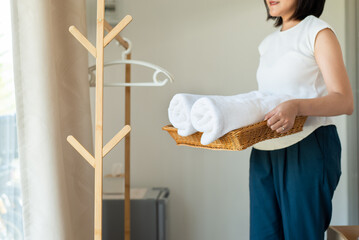 Maid woman holding stack roll towels white color in basket at home