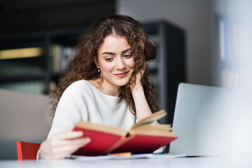 Young female student in reading library, searching information for final project, presentation. Beautiful university student preparing for final exam.