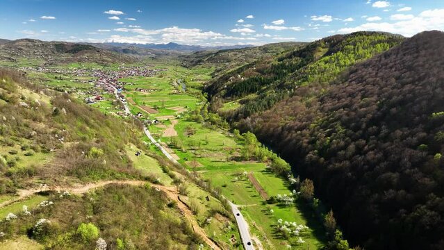 The road between the villages, with car traffic, winds through the valley of the Carpathian Mountains, flanked by forests on the mountainsides in springtime, nestled between villages B&acirc;rsana Str&acirc;mtura