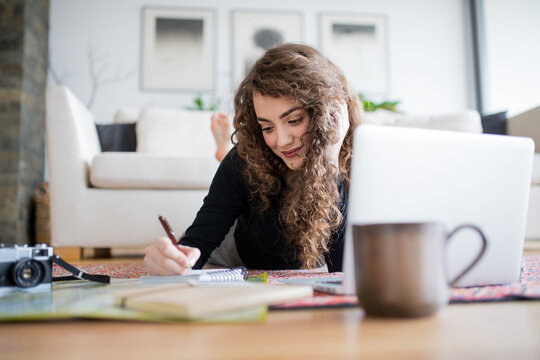 Beautiful woman planning summer vacation abroad, going on trip alone. Working on itinerary, writing notes.