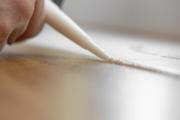 master of interior decoration, smears the joint of the tile and the kitchen countertop with white silicone instead of the skirting board, close-up