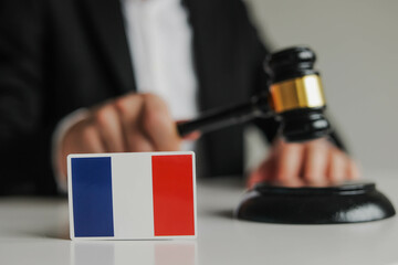 Judge's hand holding wooden gavel. Flag of France. Concept of French justice system