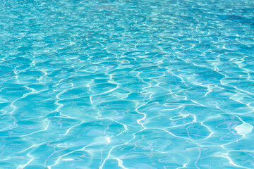 Blue swimming pool water surface and ripple wave background. Summer abstract reflection caustics in swimming pool.