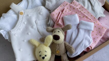 Baby and child clothes and knitted toys in carton box.