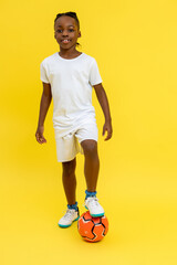 Afro-American little boy wearing white T-shirt posing with ball