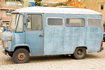 Old blue vintage vehicle parked on the street.