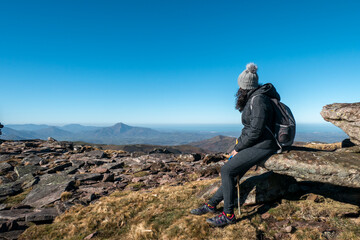 Mulher turista no alto da montanha sentada sobre uma rocha a apreciar a paisagem enquanto descansa