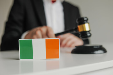 Judge's hand holding wooden gavel. Flag of Ireland. Concept of Irish justice system