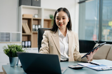 Confident business expert attractive smiling young woman typing laptop and holding digital tablet