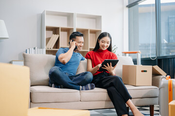 Obraz premium Asia young couple man and woman sit on couch use joystick controller play video game spend fun time together