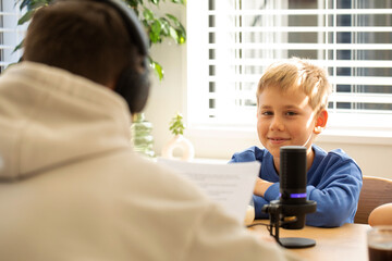Young boy happily participates in a podcast interview, with microphone. Blogging and podcasting.