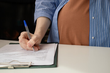 Pregnant woman signing a contract for prenatal care at a gynecology clinic, health insurance coverage, maternity services