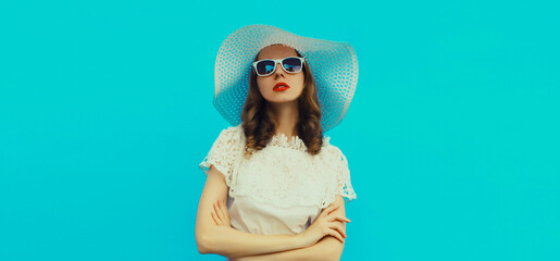 Beautiful caucasian young woman model posing wearing white summer straw hat on blue background