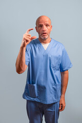 Portrait of a physiotherapist in a light blue coat and with his fingers indicating that he is tiny.