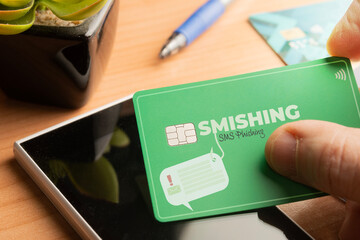 Smishing (SMS message phishing) concept: man hold a credit card over a smartphone