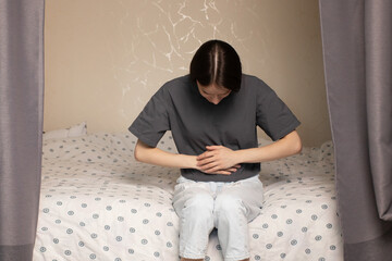 teenager has abdominal pain, teenage girl grimacing due to stomachache, discomfort in room