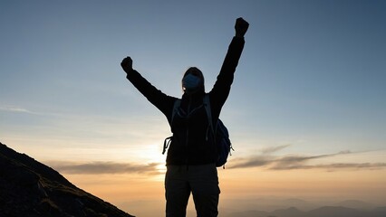 Fototapeta premium Silhouetted hiker with arms up in victory on mountain peak