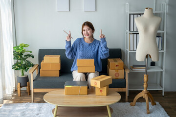 A woman is sitting on a couch with boxes in front of her. She is smiling and holding up two...