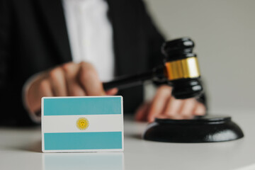 Judge's hand holding wooden gavel. Flag of Argentina. Concept of argentinian justice system
