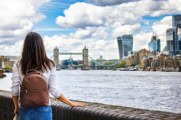 A tourist woman on a sightseeing city trip looks at the skyline of London, England, with river...