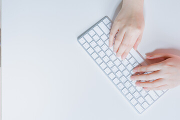 flat lay work and learn online in new normal concept from woman typing on wireless keyboard with white isolated background