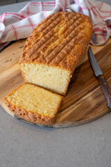 Fresh baked homemade cake on a counter ready to eat. Presented on a wooden tray with a knife to cut some pieces for the guests.
