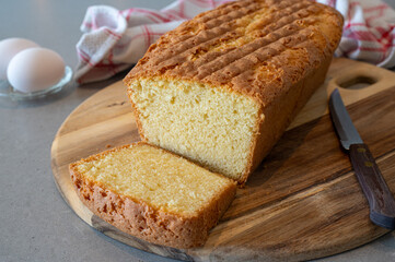 Fresh baked homemade cake on a counter ready to eat. Presented on a wooden tray with a knife to cut some pieces for the guests.