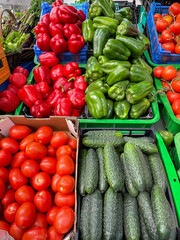 Fresh ripe vegetables red tomatoes, cucumbers and paprikas in plastic boxes on a farmers market high angle view in Porto, Portugal