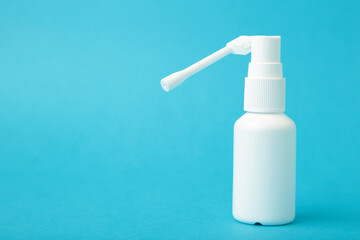 Throat spray medication in a white bottle on blue background.