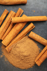 Cinnamon sticks with powder on dark background.