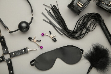 Set of erotic toys for BDSM on grey background. The game of sexual slavery with a whip, gag and...