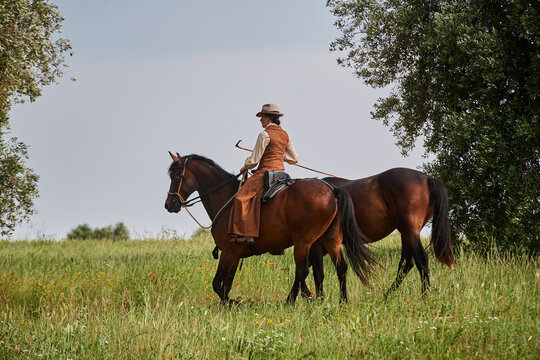 Beautiful Italian woman, riding her Maremmano horse and handling her yearling