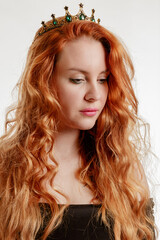 Portrait of a young beautiful red-haired woman in a crown on a light background - 806804294