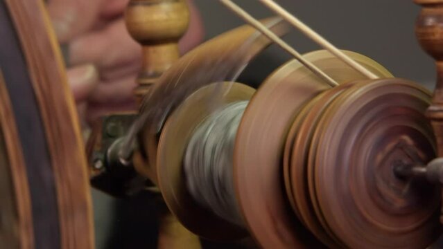 Close-up spinning wheel bobbin spins wool into yarn, traditional craft