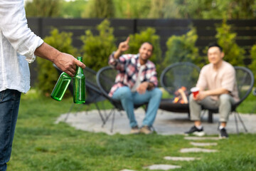 Men meeting friend with cold beer during backyard party