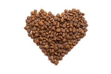 A heart laid out of dry dog food on a white isolated background. Balanced nutrition of pets. 