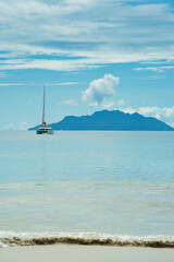 Docking yacht near the beau vallon beach, calm sea, silhouette island in the back. Mahe, Seychelles