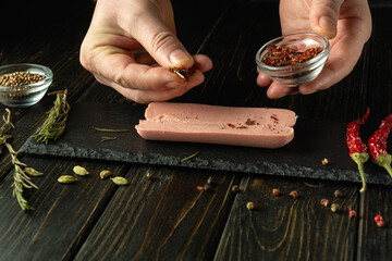 Chef prepares aromatic sausage with spices on the kitchen table. The cook hand adding dry seasoning...