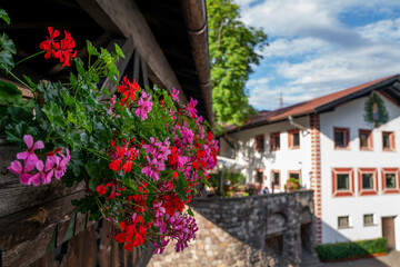 Traditional alpine houses with flowers on balcony. Colorful and picturesque village. Alpine village houses decorated with flowers street view.